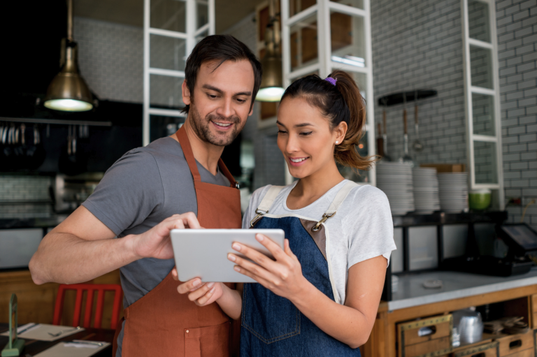 un chico y una chica mirando una tablet en un restaurante